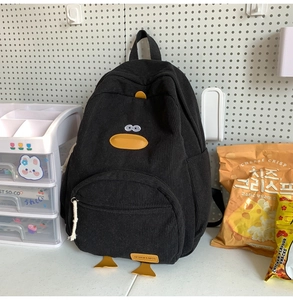 Detailed close-up of a black corduroy duck backpack with yellow accents on pegboard