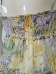 Détail d'une robe en mousseline fleurie montrant le smock et les bords volantés