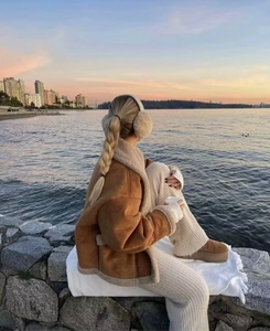 Braune Wildlederjacke mit Lammfellfutter und Strickhose vor Sonnenuntergang am Strand
