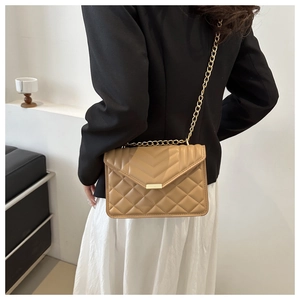 Detail of khaki quilted crossbody bag with gold chain strap on a fashion model