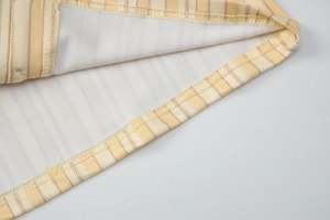 Vue macro des détails de couture et de finition sur le t-shirt à rayures jaunes et blanc