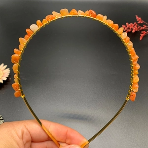 Detail of handmade gold metal headband featuring wrapped orange natural crystal stones