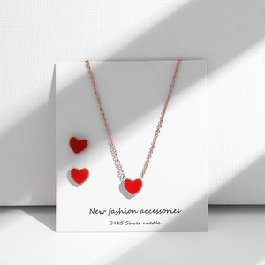 Detail view of heart-shaped necklace and S925 silver needle earrings in rose gold finish