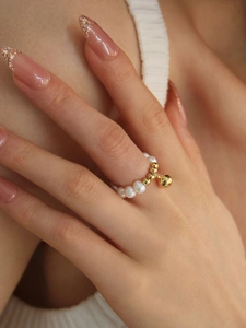 Gros plan d'une bague en perles d'eau douce avec pendentif boule dorée sur mannequin
