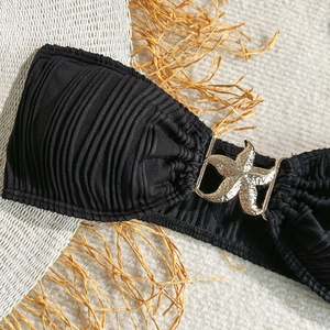 Close-up of black ruched bikini fabric with a detailed gold starfish metal buckle charm