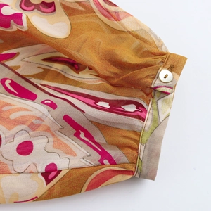 Detailed macro view of chiffon shirt cuff with floral paisley print and white button