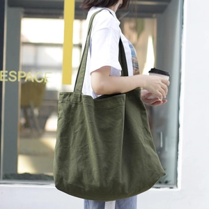 Minimalist army green canvas tote bag with wide straps shown on model in urban setting