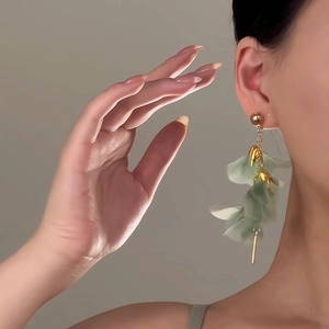Elegant floral mesh earrings with light green petals and gold long tassels on model