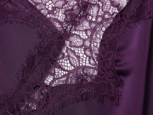 Gros plan sur satin violet foncé avec des motifs délicats de dentelle de cils