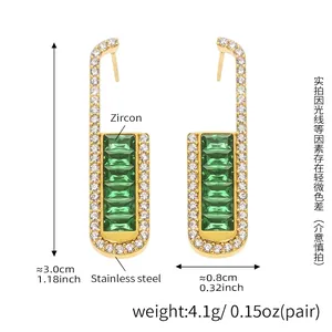 Detail showing gold earrings with green emerald-cut zircon and white side stones
