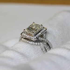 Primer plano de anillo halo plateado con piedra cuadrada y banda de pavé trenzada