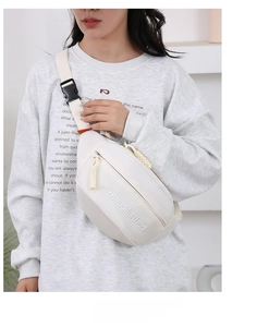 Close-up of white canvas waist bag featuring embossed logo and woven zipper detail