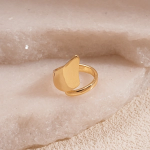 Detailed macro view of an irregular 18K gold-plated geometric ring on white natural stone