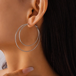 Close-up of model wearing silver multi-layer geometric double hoop earrings in a minimalist style