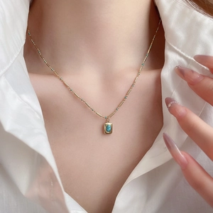 Detail of bohemian gold chain necklace with a small rectangular turquoise stone pendant