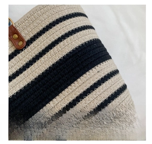 Close-up of woven black and white fabric texture with leather strap and metal rivets