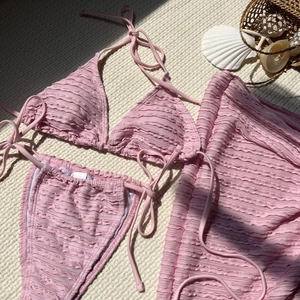 Pink seersucker three-piece bikini set with wrap skirt and beach vacation accessories