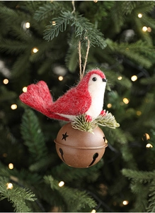 Detail of red felt bird ornament with bronze bell on glowing Christmas tree