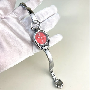 Macro view of silver bracelet watch featuring a minimalist red dial with Roman numerals