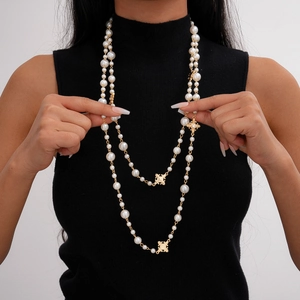Collier de perles multicouche élégant avec croix dorée et pendentifs emblème sur un mannequin