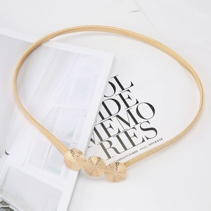 Detailed close-up of champagne gold spring metal belt with triple textured circular buckle