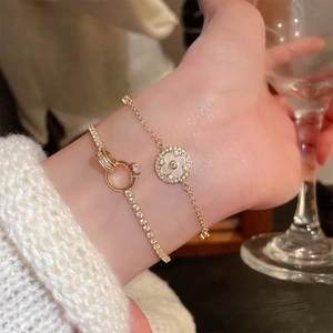 Detail of gold clover charm bracelet with white shell and sparkling zircon tennis chain