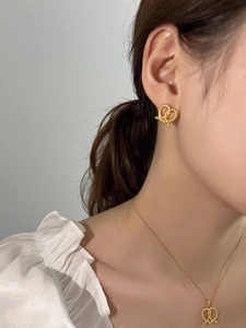 Close-up of elegant gold twisted rope knot earring and necklace set worn by a model