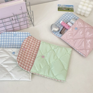 Detailed view of quilted sanitary pad storage bags in soft pastel colors and snap button