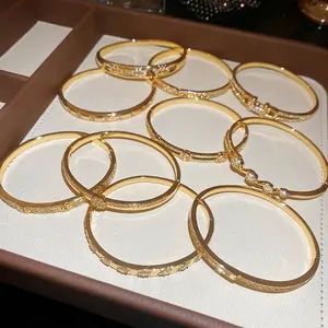 Bracelets joncs minimalistes plaqués or avec zircone en divers designs sur un présentoir