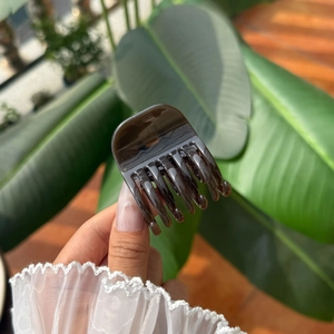 Detailed view of an amber resin hair claw clip held against a natural sunlit background