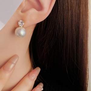 Gros plan d'un mannequin portant une boucle d'oreille perle dorée et pierre précieuse