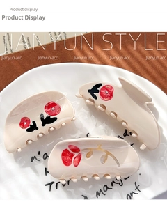 Detail of cream rose hair claw clips with floral patterns and rhinestones on ceramic tray