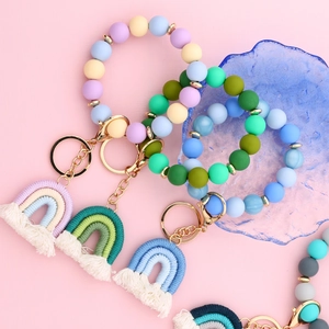 Detail of colorful silicone bead bracelet keychain with macrame rainbow tassels in gold hardware