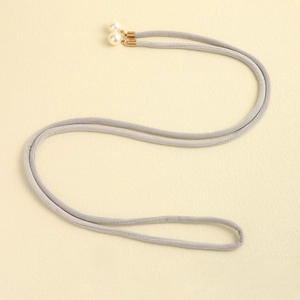 Detail of grey velvet cord accessory with gold metal caps and elegant faux pearls