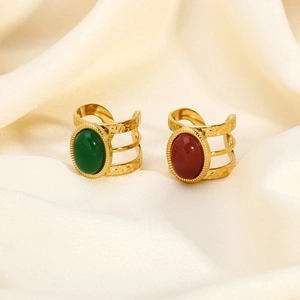 Detail of vintage gold open rings with green and red stones on cream silk fabric