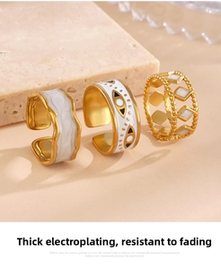 Macro detail of white enamel rings with evil eye charm and gold-plated geometric designs