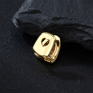 Macro shot of gold-plated hollow heart-shaped single tooth grillz on dark mineral stone