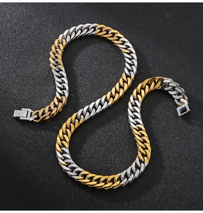 Close-up of dual-tone gold and silver Cuban link necklace on a dark textured background