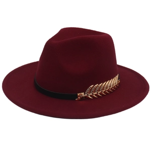 Detail of dark red wool fedora hat featuring a black band and gold leaf metal accessory