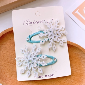 Close-up of two handmade light blue fabric wrapped hair clips with glittery snowflakes