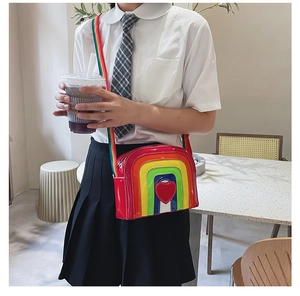 Close-up of vibrant rainbow crossbody bag with red heart patch and striped strap detail
