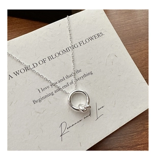 Detailed view of S925 sterling silver knotted ring pendant necklace on textured paper