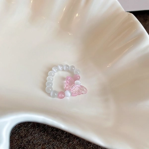 Detailed shot of beaded flower ring with pink butterfly on a white shell plate