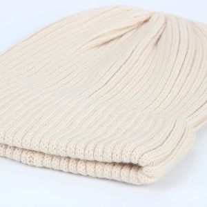 Close-up of beige ribbed knit beanie texture showing detailed soft vertical stripes
