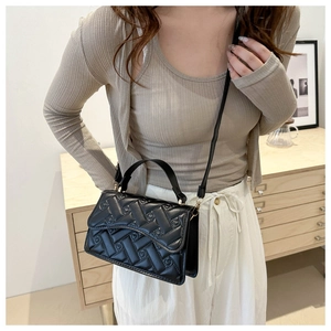 Detail of black quilted leather handbag showing woven texture on a camel sweater background