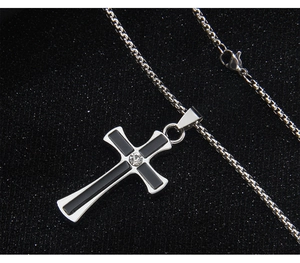 Macro shot of silver cross necklace with black inlay and central sparkling rhinestone detail