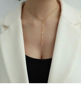 Gros plan d'un élégant collier en Y doré avec un long pendentif sur un mannequin