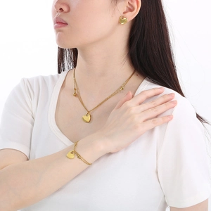 Model wearing 18K gold plated stainless steel heart necklace, bracelet, and stud earrings set