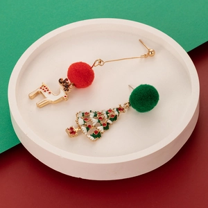 Close-up of Christmas reindeer and tree earrings with red and green fur balls on a tray
