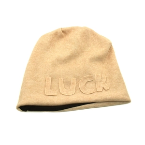 Detail of beige knit beanie showing the LUCK letter patch and black inner lining fabric